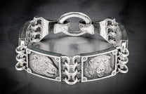 Silver metal bracelet featuring two detailed bear head engravings and an ornate chain link design.