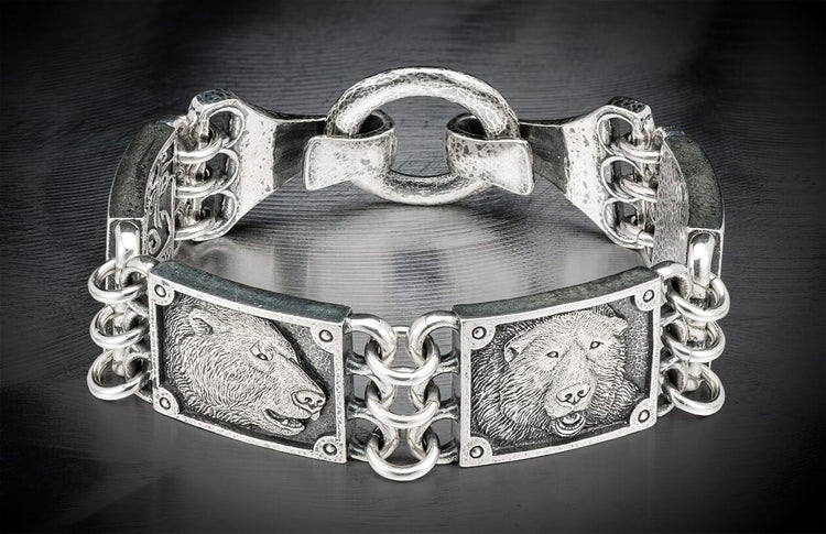 Silver metal bracelet featuring two detailed bear head engravings and an ornate chain link design.