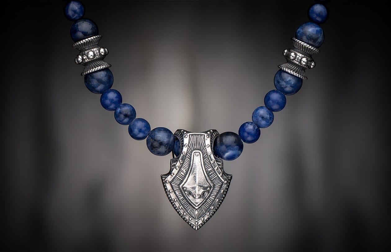 Sodalite Shield necklace with an ornate silver-toned pendant and round blue sodalite beads.