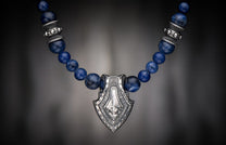 Sodalite Shield necklace with an ornate silver-toned pendant and round blue sodalite beads.