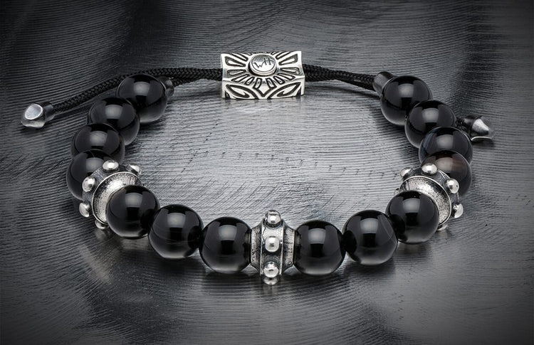 Black sardonyx bead bracelet with silver decorative spacers, a slider charm featuring 'WH' logo, and black braided cord.