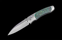 Folding knife with a silver blade featuring a 'Wt' logo, green and black patterned handle scales, and metallic silver accents.