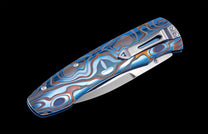 Folding knife with anodized and color-laser engraved frame on a black background