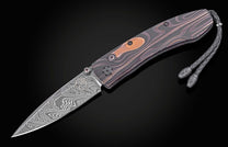 Dark patterned folding knife with damascus steel blade and wood inlay handle, featuring braided lanyard, side view on black background