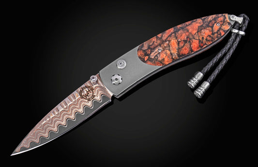 Coral-patterned folding knife with damascus steel blade and textured handle, by B05 Ignis, featuring braided lanyard and silver hardware, side view on black background