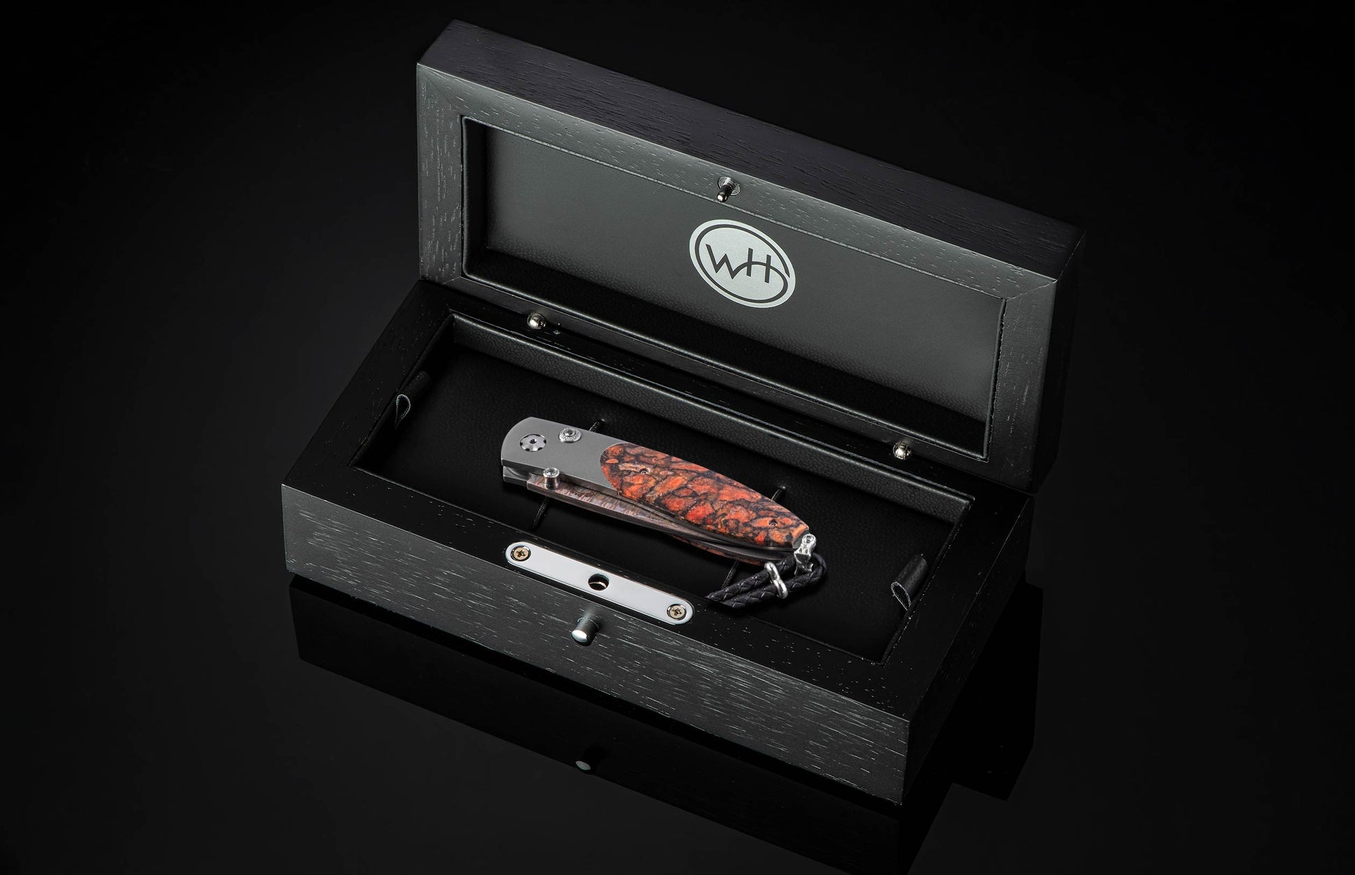 Coral-patterned folding knife with textured handle by B05 Ignis, displayed in sleek black presentation box with silver hardware, top-down view.