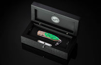 William Henry folding knife with mokume gane and Irish Green Stone in a wooden display case