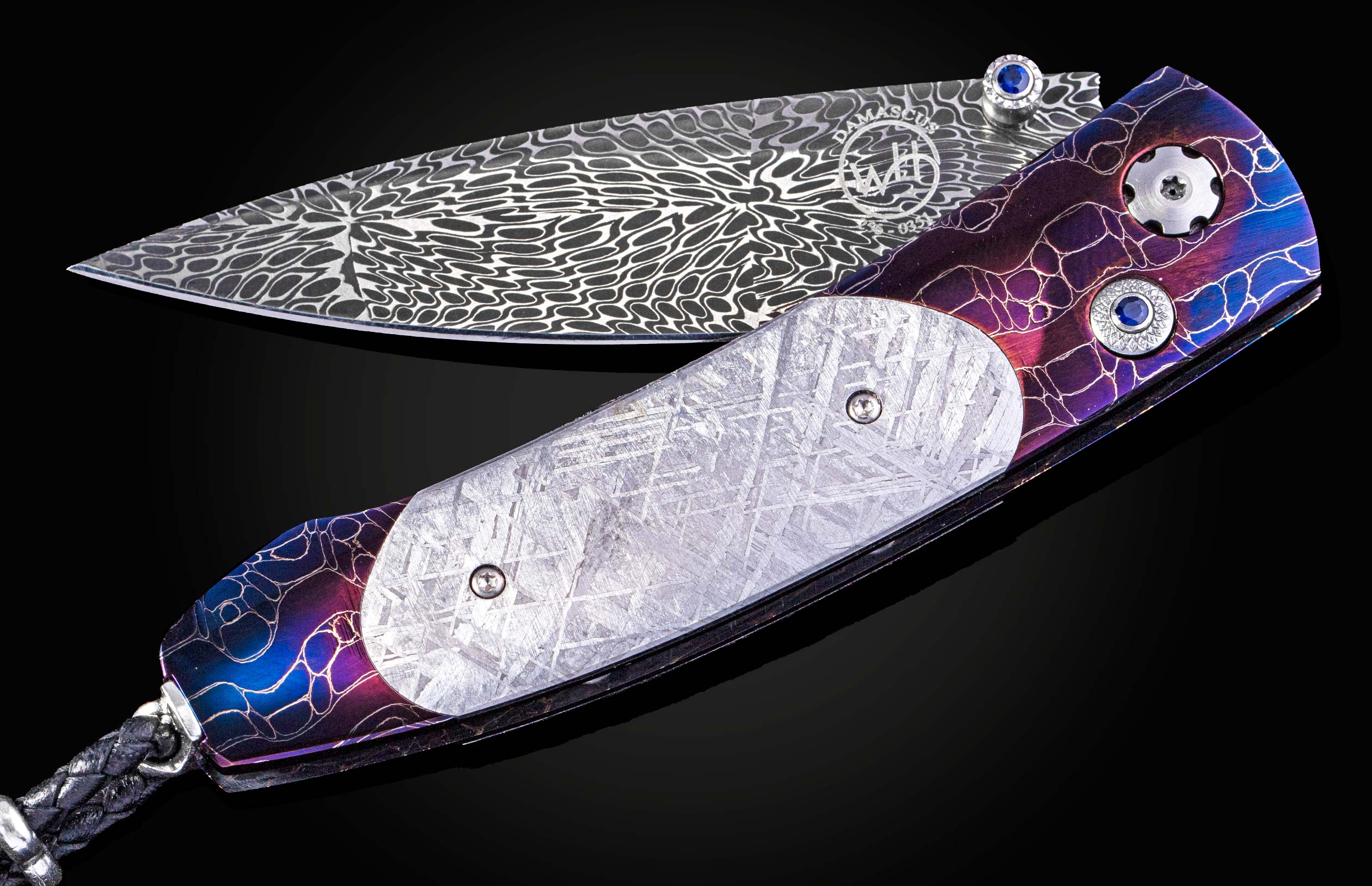 William Henry knife with a colorful handle and engraved blade on a black background