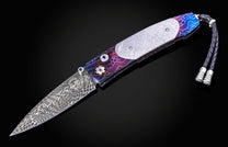 William Henry knife with a colorful handle and engraved blade on a black background