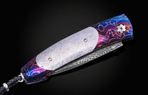 William Henry knife with a colorful handle and engraved blade on a black background