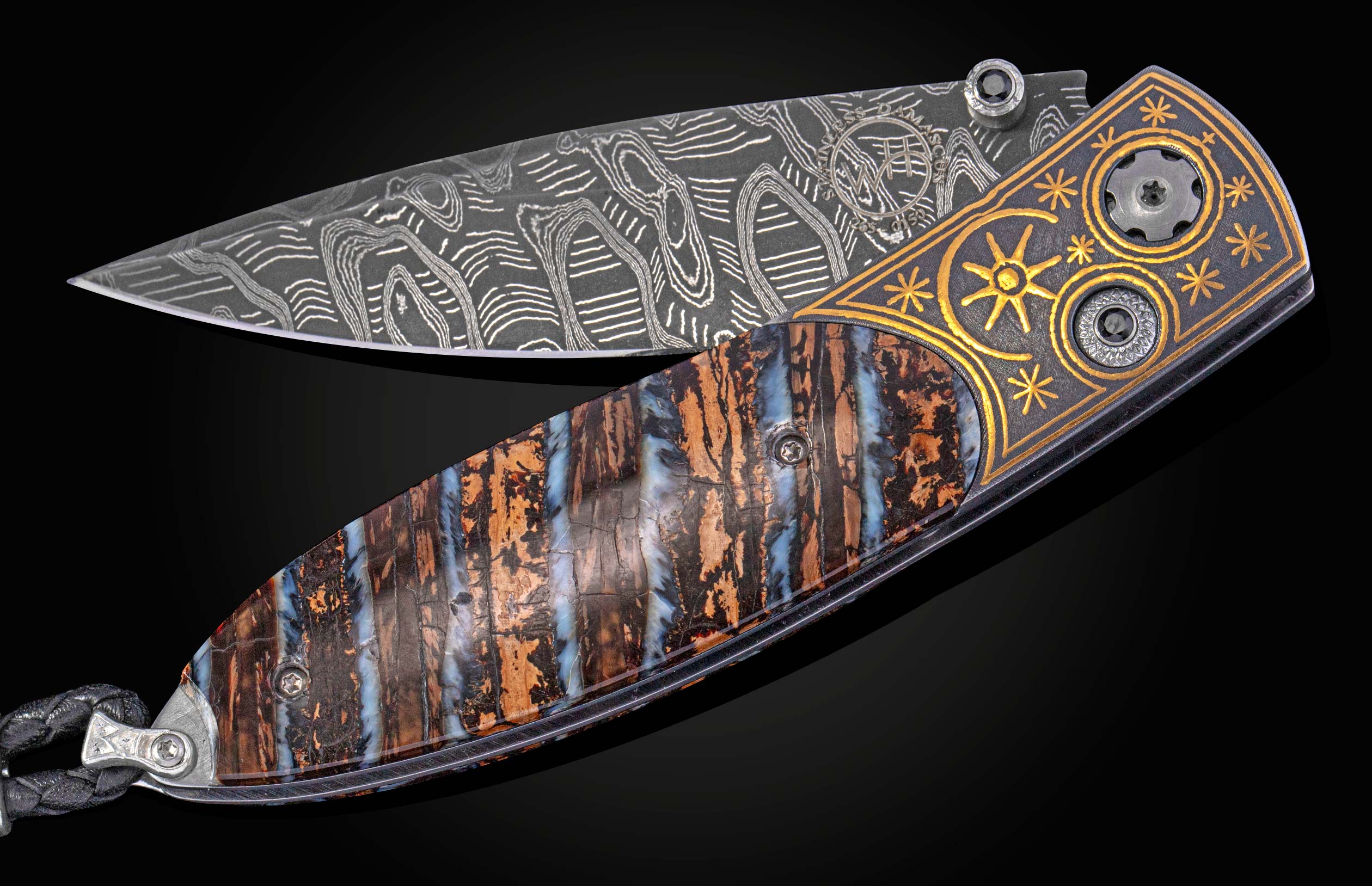 Open folding knife with a patterned Damascus steel blade, a handle of brown and blue fossilized material, and a black metal section with gold star engravings, finished with a braided black leather lanyard.
