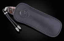 Folding knife with a blue and orange fossil handle, partially in a black leather case with an embossed logo and braided lanyard.