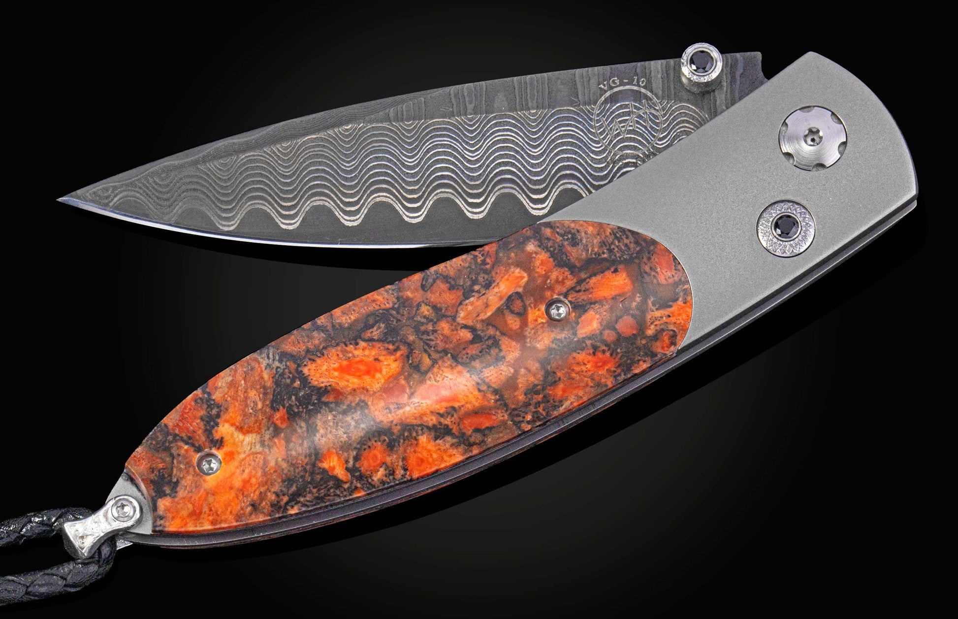 Gray folding knife with a wavy Damascus VG-10 blade, black accent stones, and an orange and black patterned handle scale.