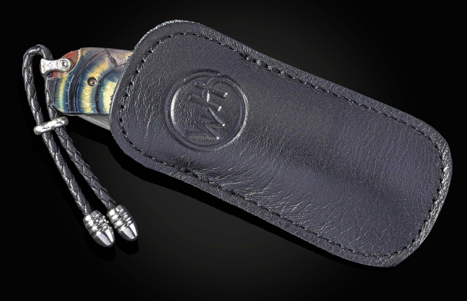 Folding knife with Wave Mokume, fossil mammoth tusk, and a damascus blade on a black background