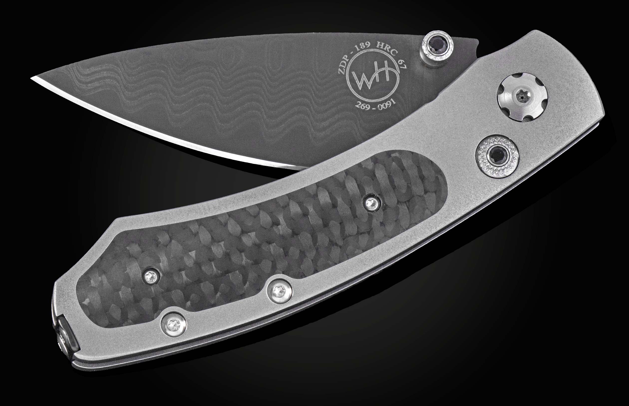 Dark gray folding knife with a wavy pattern blade and metallic gray handle with textured carbon fiber inserts.