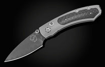 Grey folding knife with dark carbon fiber handle and wavy Damascus blade pattern, shown diagonally on black.