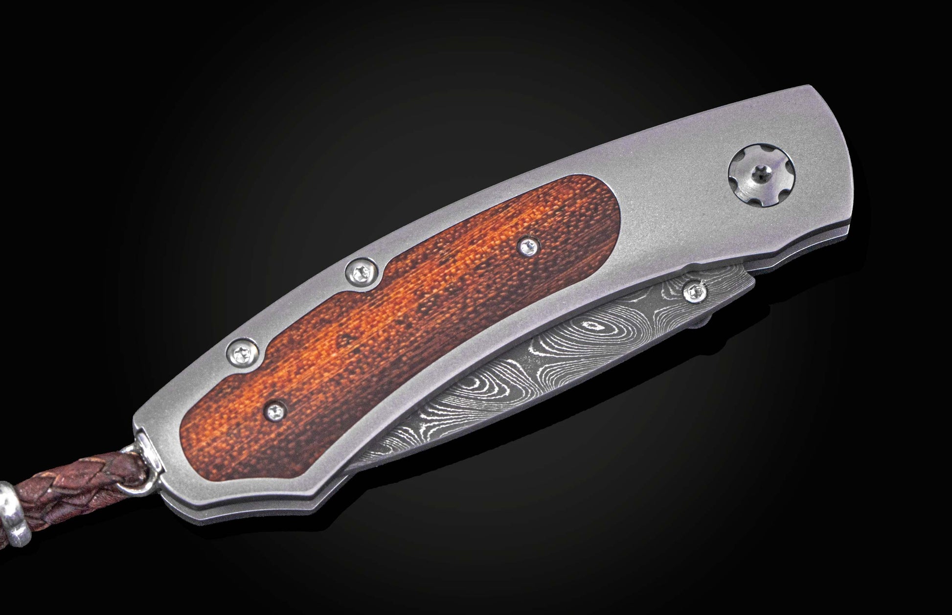 Folding knife with wooden handle and damascus blade on a black background