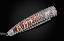 Folded pocket knife with detailed eagle engraving and brown burl wood inlay, by American Eagle, featuring ornate silver frame and star-patterned design, side view on black background