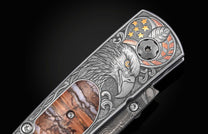 Stainless steel folding knife with engraved eagle and American flag design, featuring copper accents and a marbled wood inlay, side view.