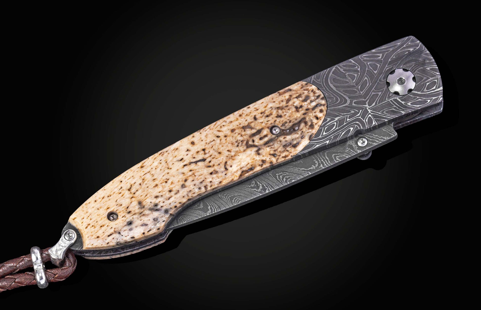 Folding knife with damascus blade and fossil walrus bone scales on a black background