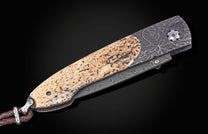 Folding knife with damascus blade and fossil walrus bone scales on a black background