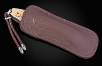 Folding knife with damascus blade and fossil walrus bone scales on a black background