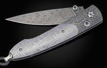 Decorative knife with damascus blade and meteorite handle on a black background partially open