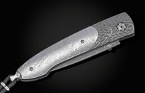 Decorative knife with damascus blade and meteorite handle on a black background shown closed