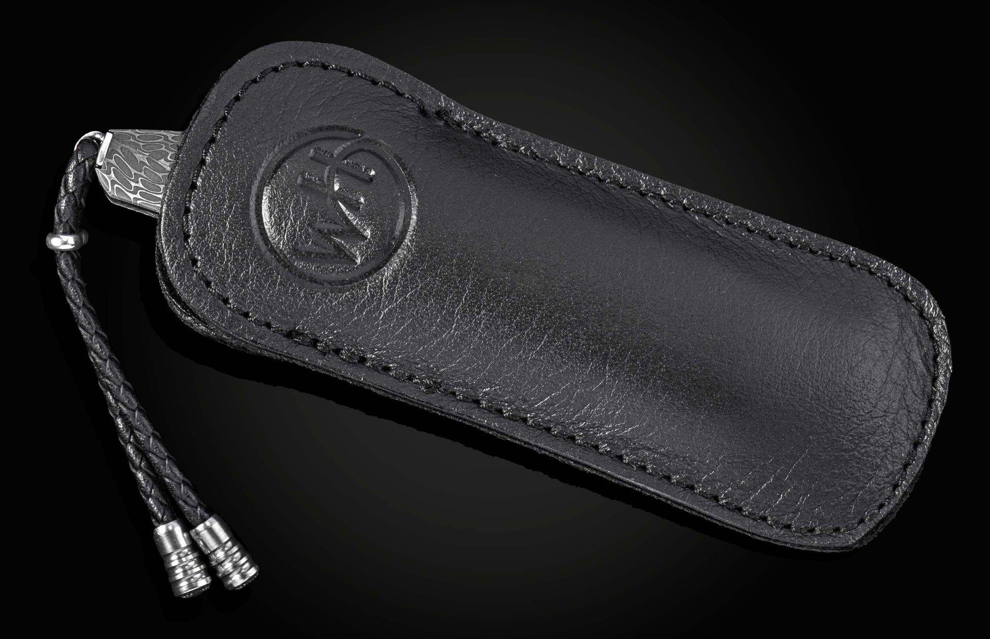 Black leather knife sheath with embossed logo and braided cord, by Mammuthus, featuring stitched edges and textured surface, side view.