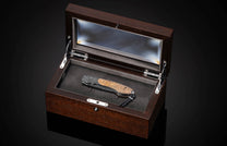 Folding knife with wooden handle and decorative blade on a black background