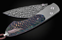 Damascus steel blade with intricate wave pattern and iridescent pinecone-textured handle by B12, side view on black background