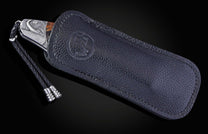 Foldable knife with fossil mammoth tusk, hand engraving, and damascus blade on a black background