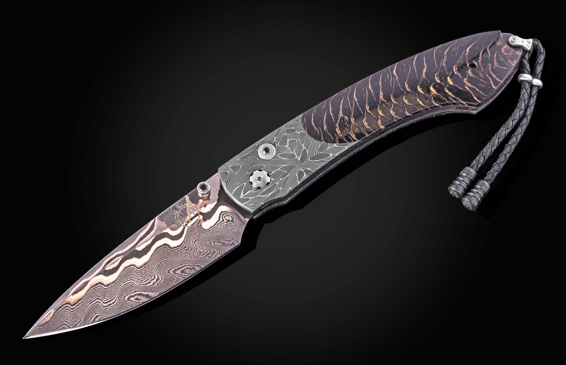 Damascus steel knife with black and gold marbled handle by B12, featuring braided lanyard and textured bolsters, side view on dark background