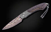 Damascus steel knife with black and gold marbled handle by B12, featuring braided lanyard and textured bolsters, side view on dark background