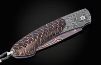 Luxury black forest knife with damascus steel blade and copper-veined handle, side view on dark background