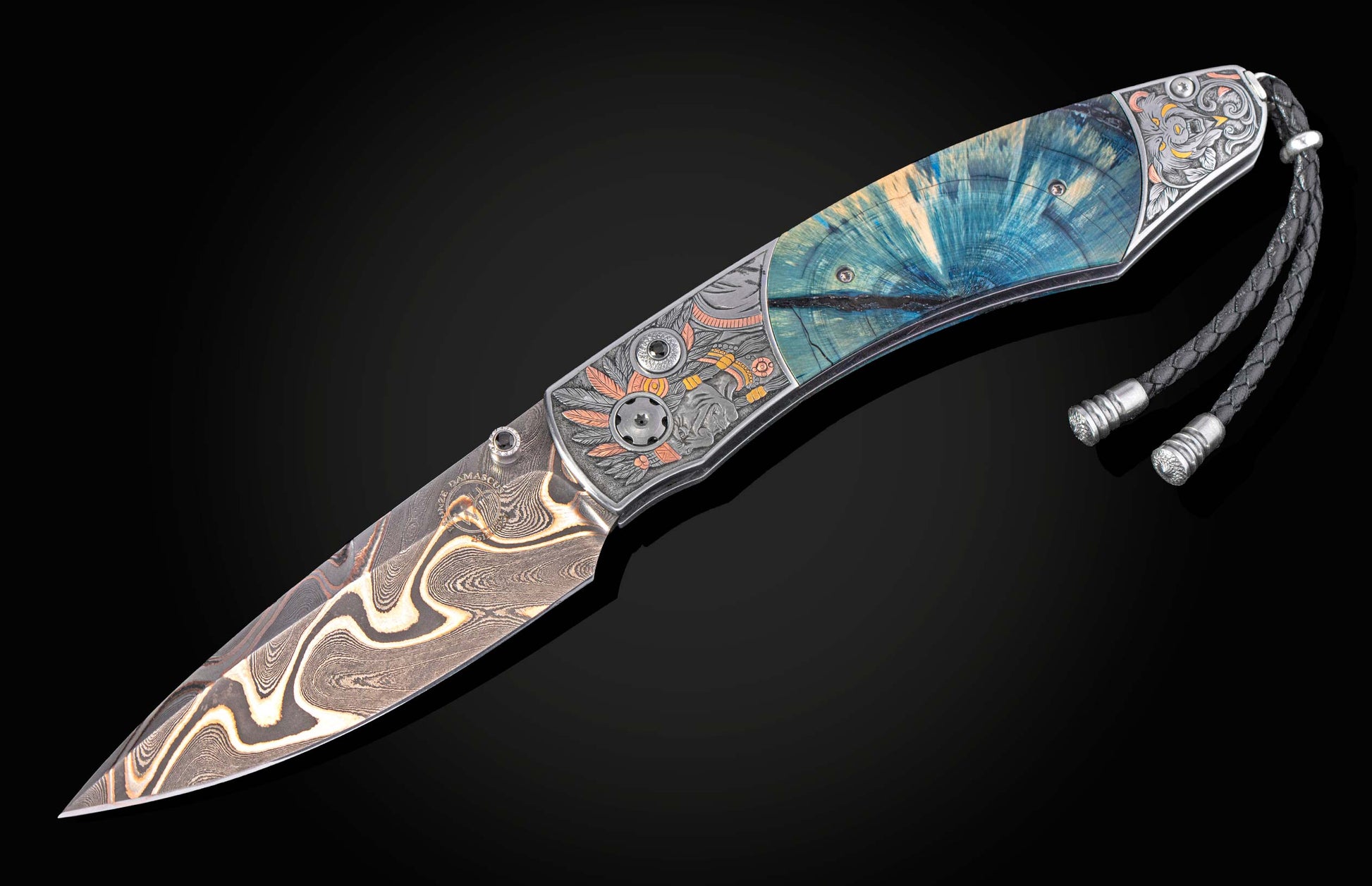 Damascus folding knife with blue stabilized wood handle, engraved metal accents, and a braided black leather lanyard.