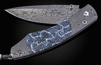 Folding knife with Damascus steel blade and fossil coral handle on a black background