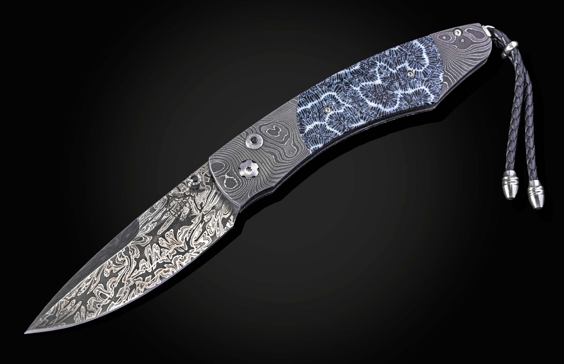Folding knife with Damascus steel blade and fossil coral handle on a black background