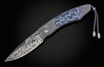 Folding knife with Damascus steel blade and fossil coral handle on a black background