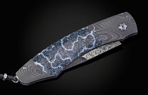Folding knife with Damascus steel blade and fossil coral handle on a black background