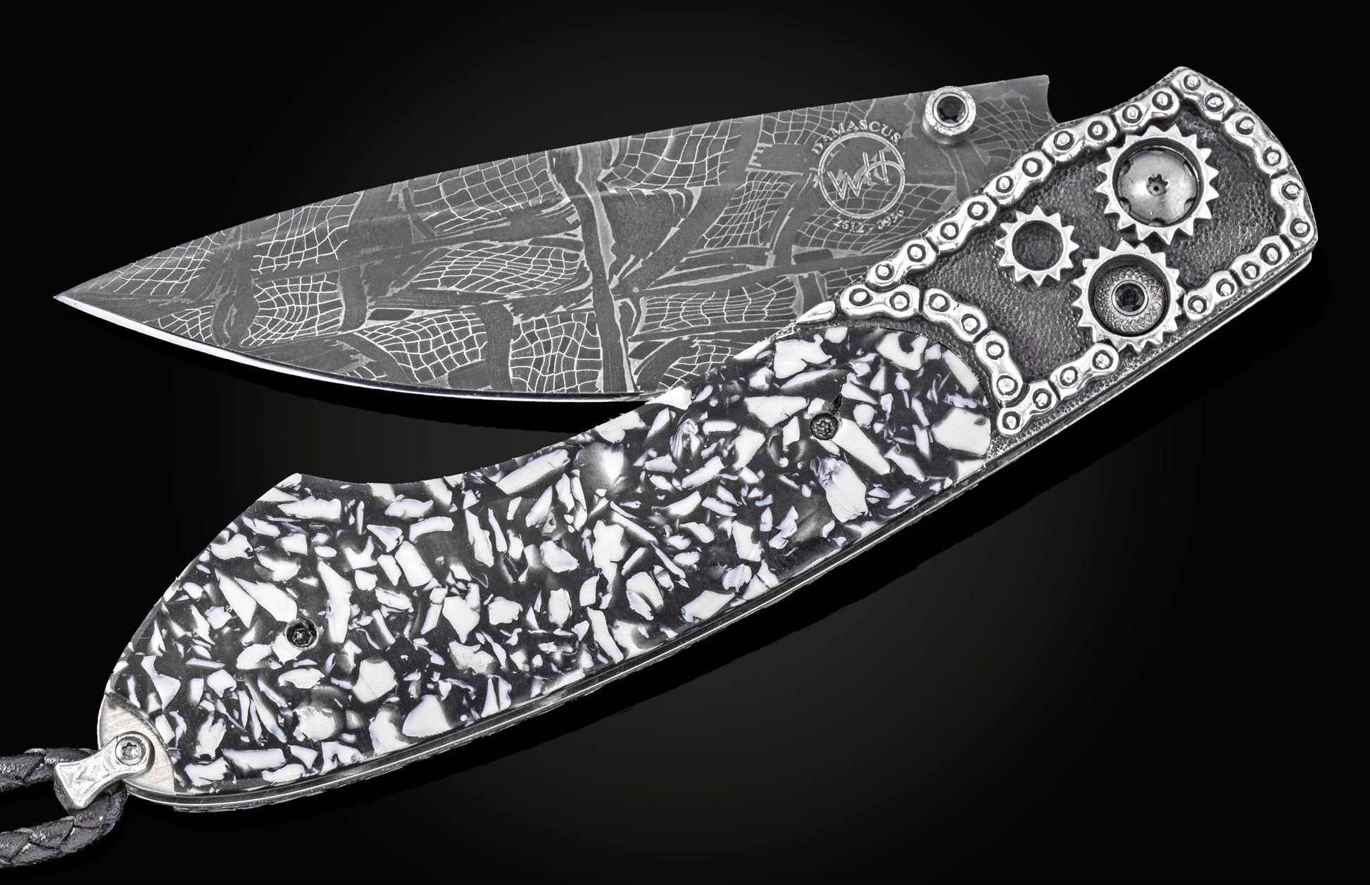 Damascus steel folding knife with black and white mosaic handle, gear accents, and chain detailing by B12, side view on black background