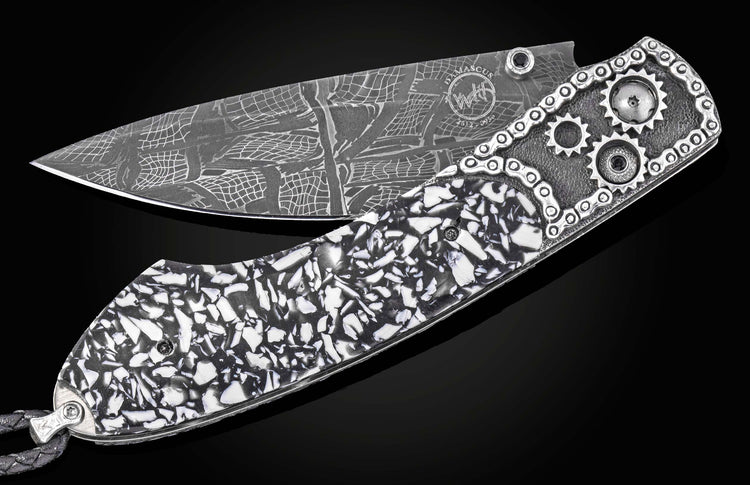 Damascus steel folding knife with black and white mosaic handle, gear accents, and chain detailing by B12, side view on black background