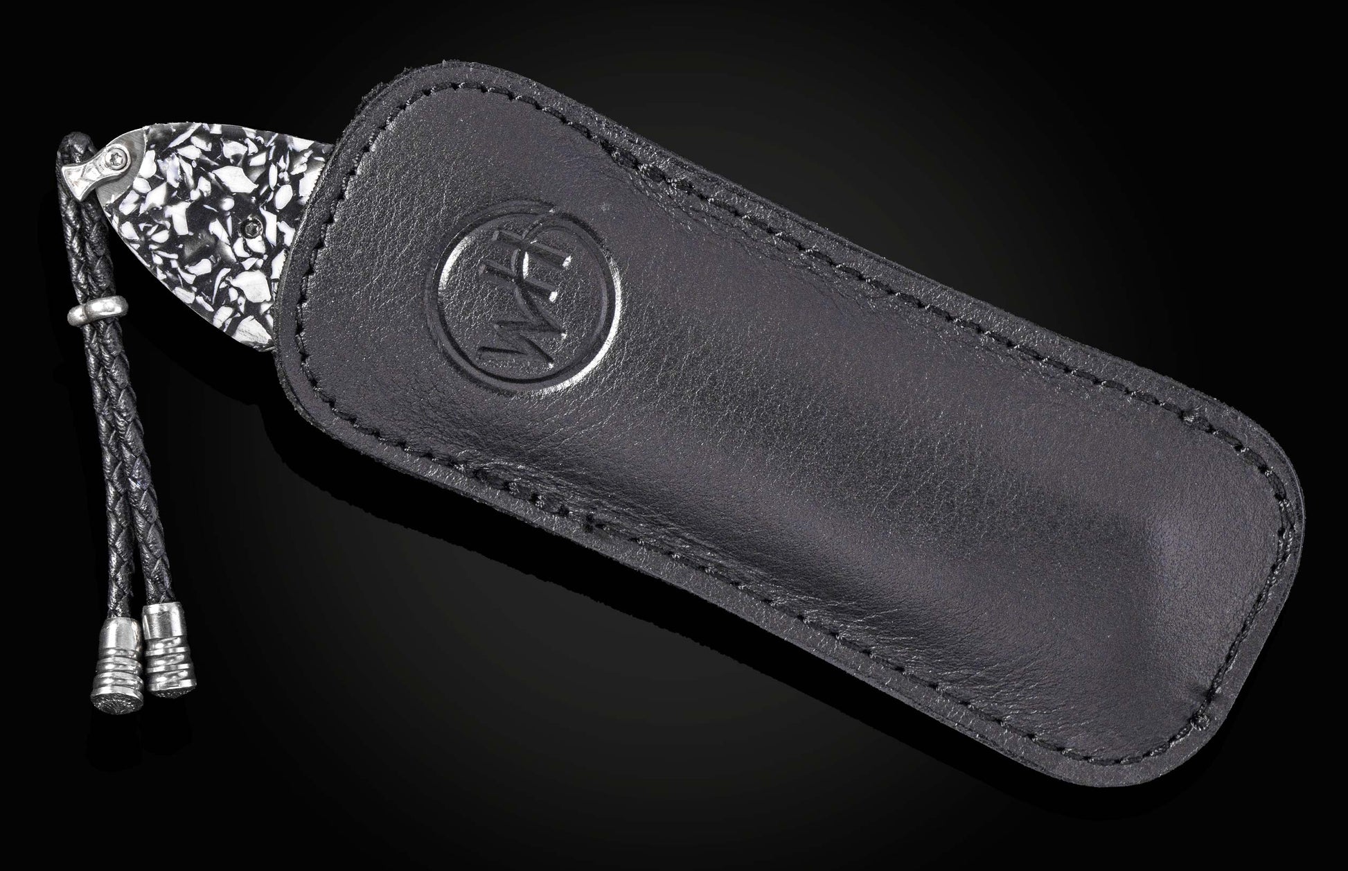 Luxury Damascus steel knife with black leather sheath by B12, featuring embossed logo and braided cord accent, side view on dark background