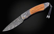 Folding knife with wood handle and intricate hand engraving of historical event. Knife shown open.