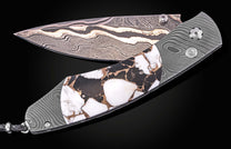 Luxury Damascus steel knife with black and white marbleized handle, by B12, featuring wave-pattern blade and textured grip, side view on black background