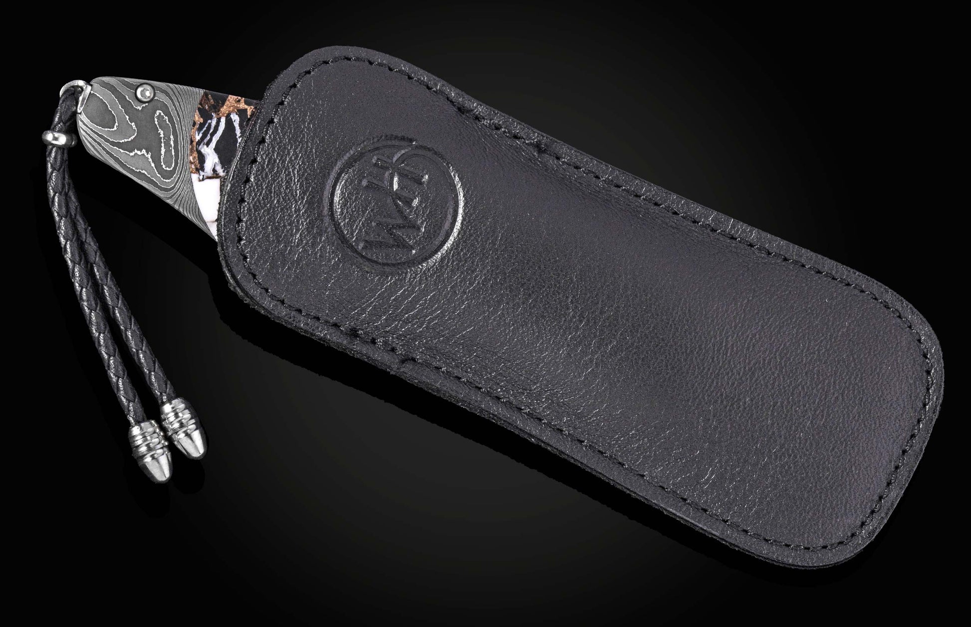 Luxury Damascus steel knife with marbled handle and black leather sheath by B12, featuring braided cord and embossed logo, side view on dark background