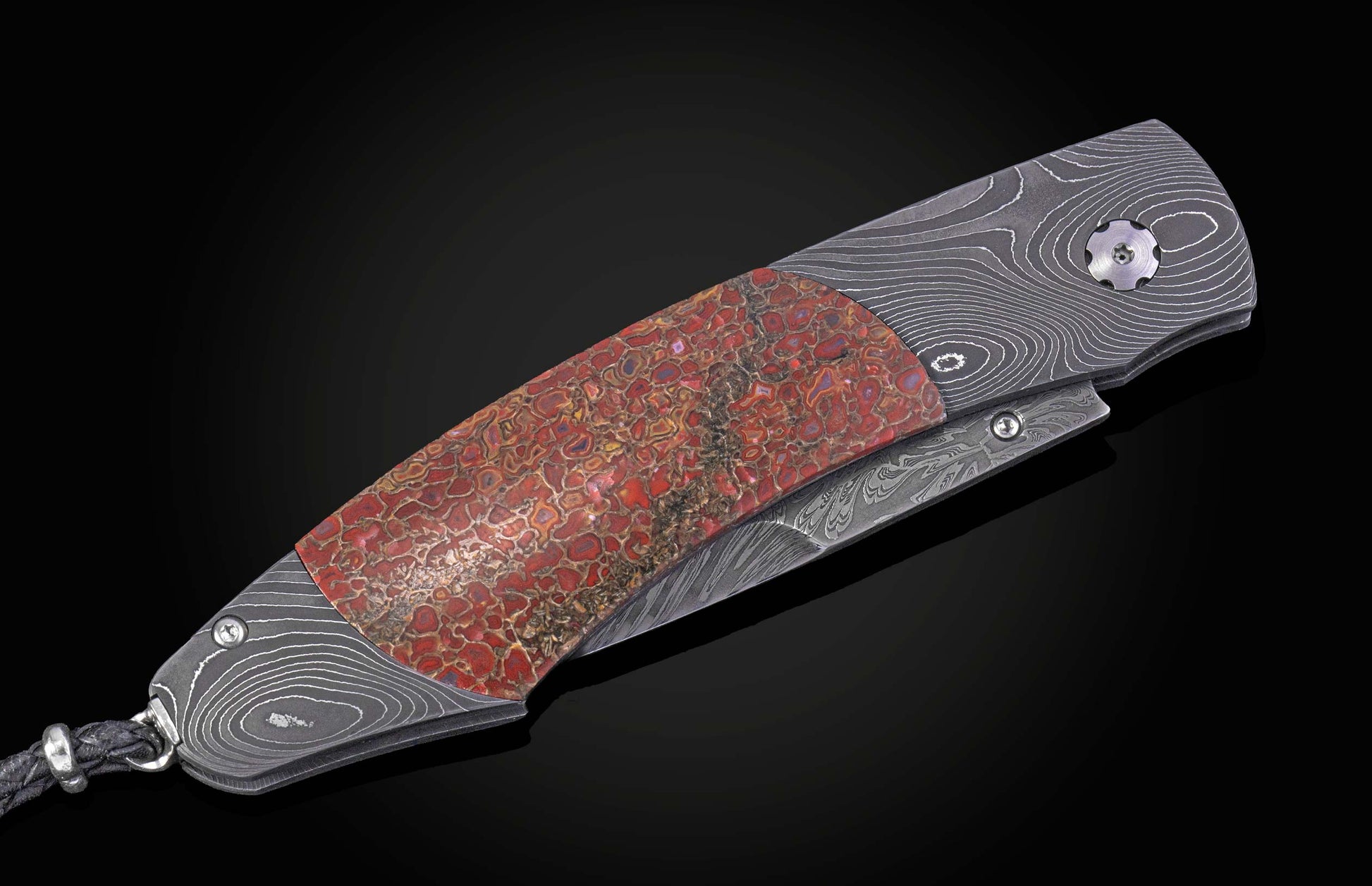 Decorative knife with a damascus blade and fossilized dinosaur bone scales on a black background