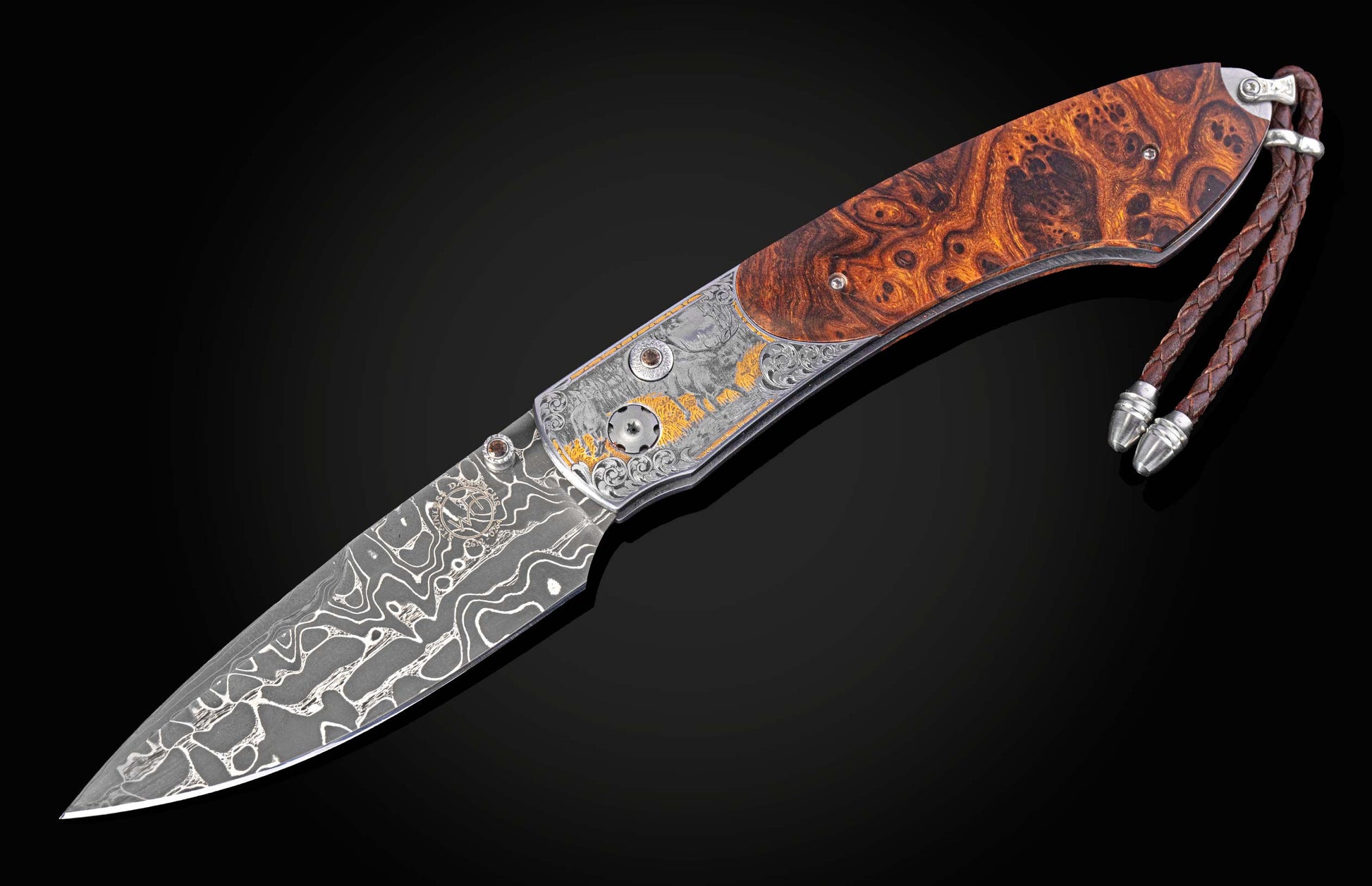 Custom folding knife with a Damascus steel blade, burl wood handle, and engraved bolster featuring gold elk designs and a leather lanyard.