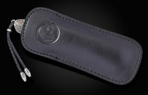 B12 Frontier Tales knife in a black leather sheath, featuring an embossed logo, braided lanyard, and silver-toned accents.