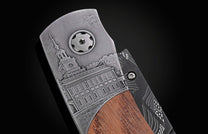Knife with an engraved Independence Hall on textured gray metal, brown wood, and a black patterned handle.